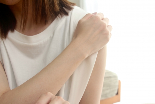 左肩を右手で抑え痛がる女性